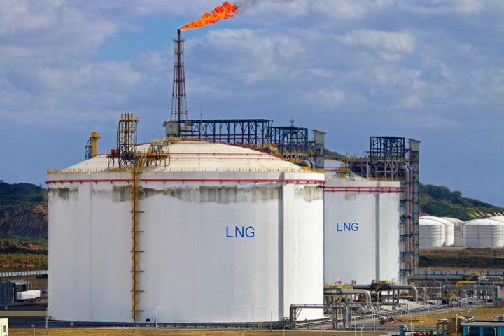 LNG storage tanks at regasification terminal Picture of large LNG (Liquefied natural gas) tanks at LNG regasification terminal, with gas flare stack