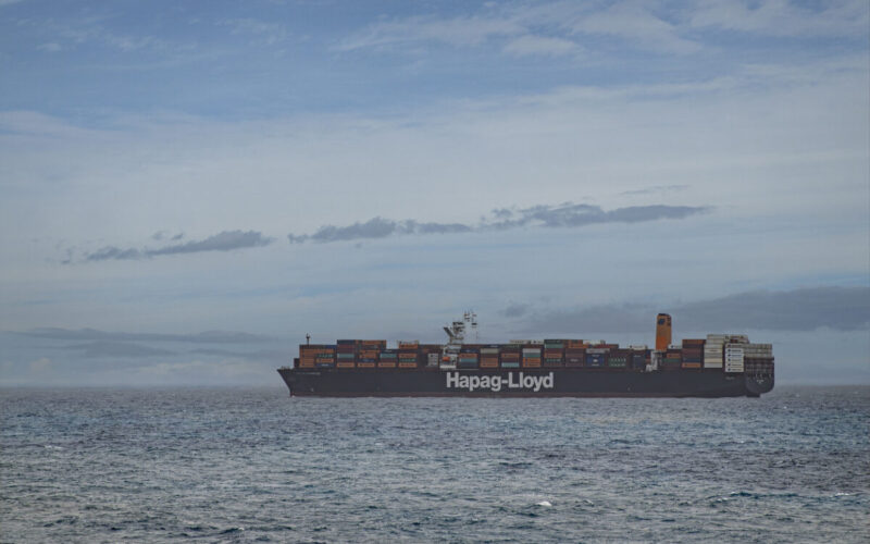 Limon Bay, Colon, Panama - July 24, 2023: Hapag-Lloyd container ship in front of Port under blue cloudscape. Containers add colors